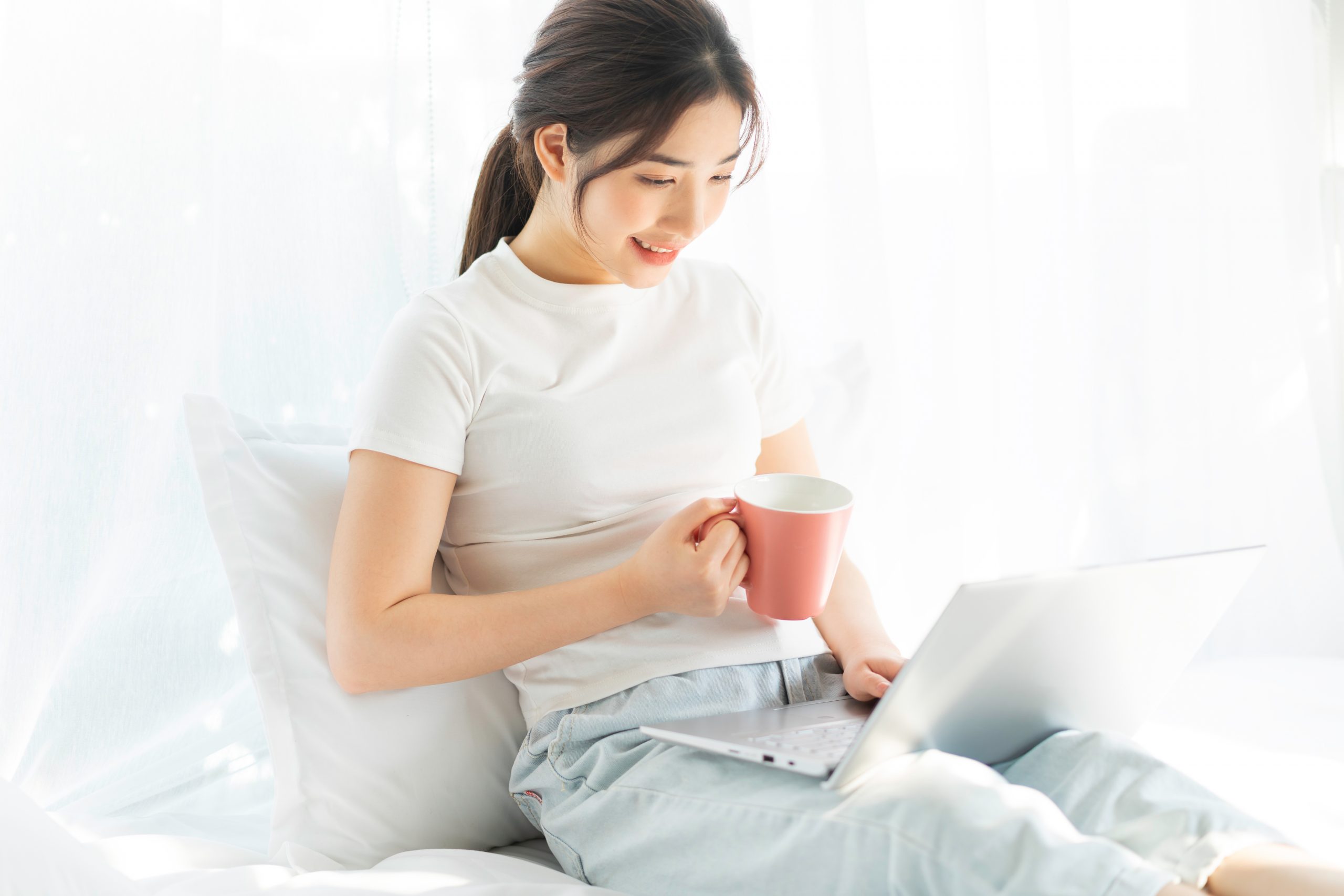 Young Asian woman sitting on bed working watching home entertain